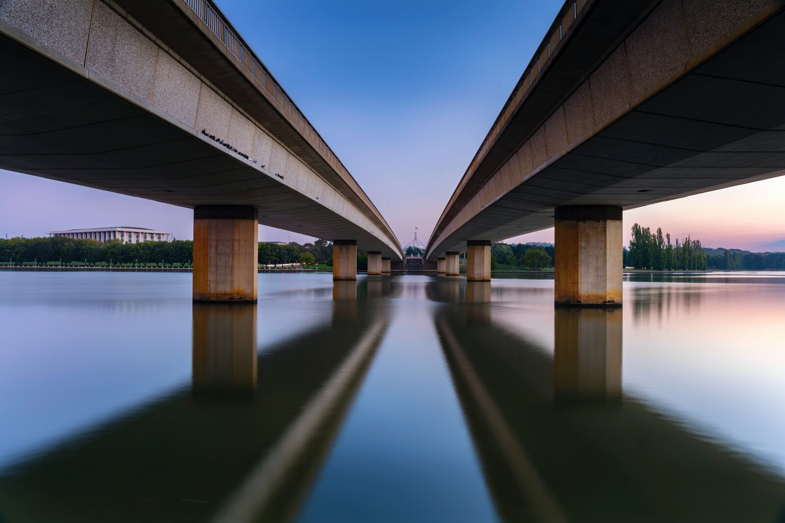 View beneath Commonwealth Avenue Bridge across Lake Burley Griffin at dusk, looking towards Parliament House, Canberra